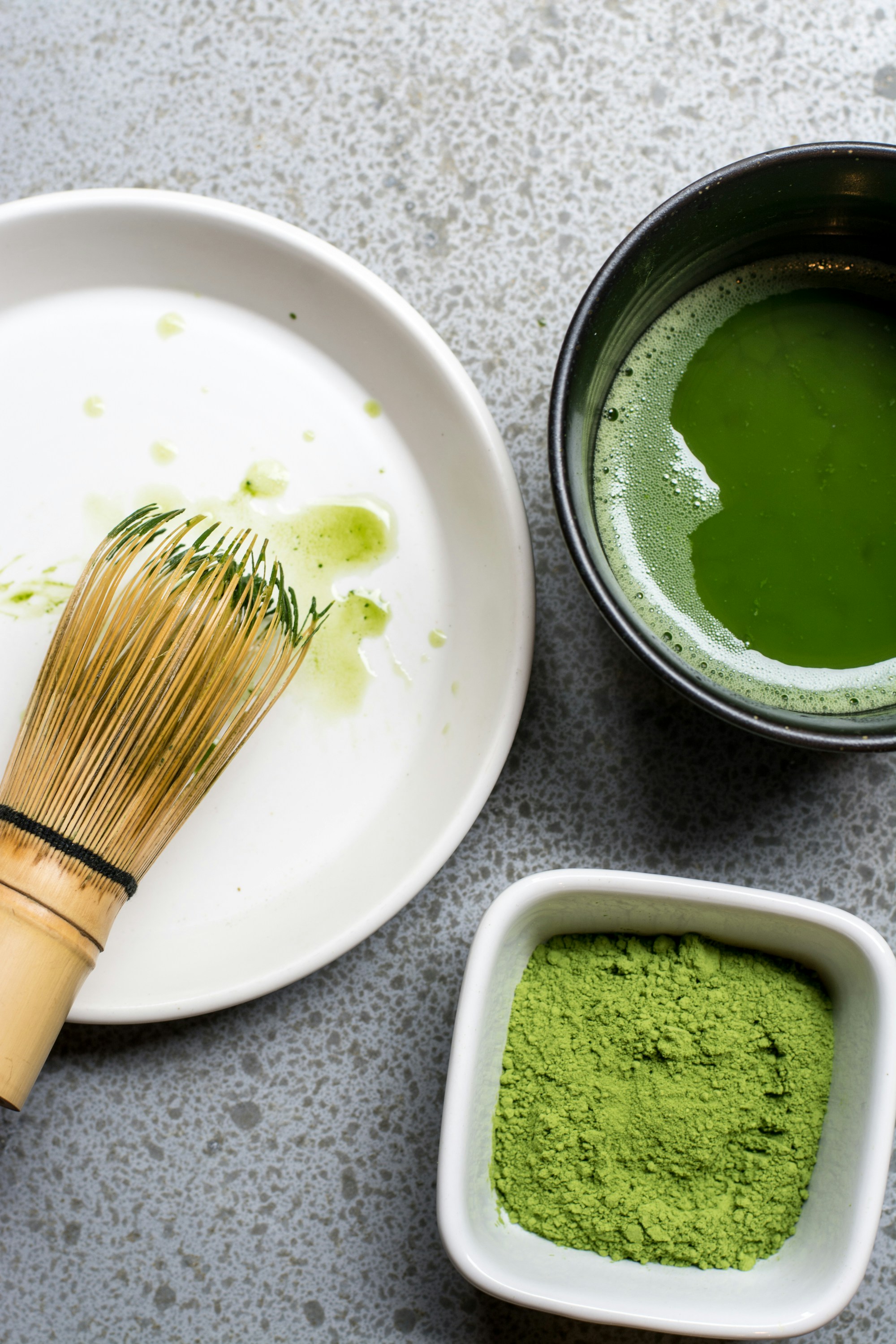 Bamboo chasen, whisked matcha, and raw matcha powder side by side