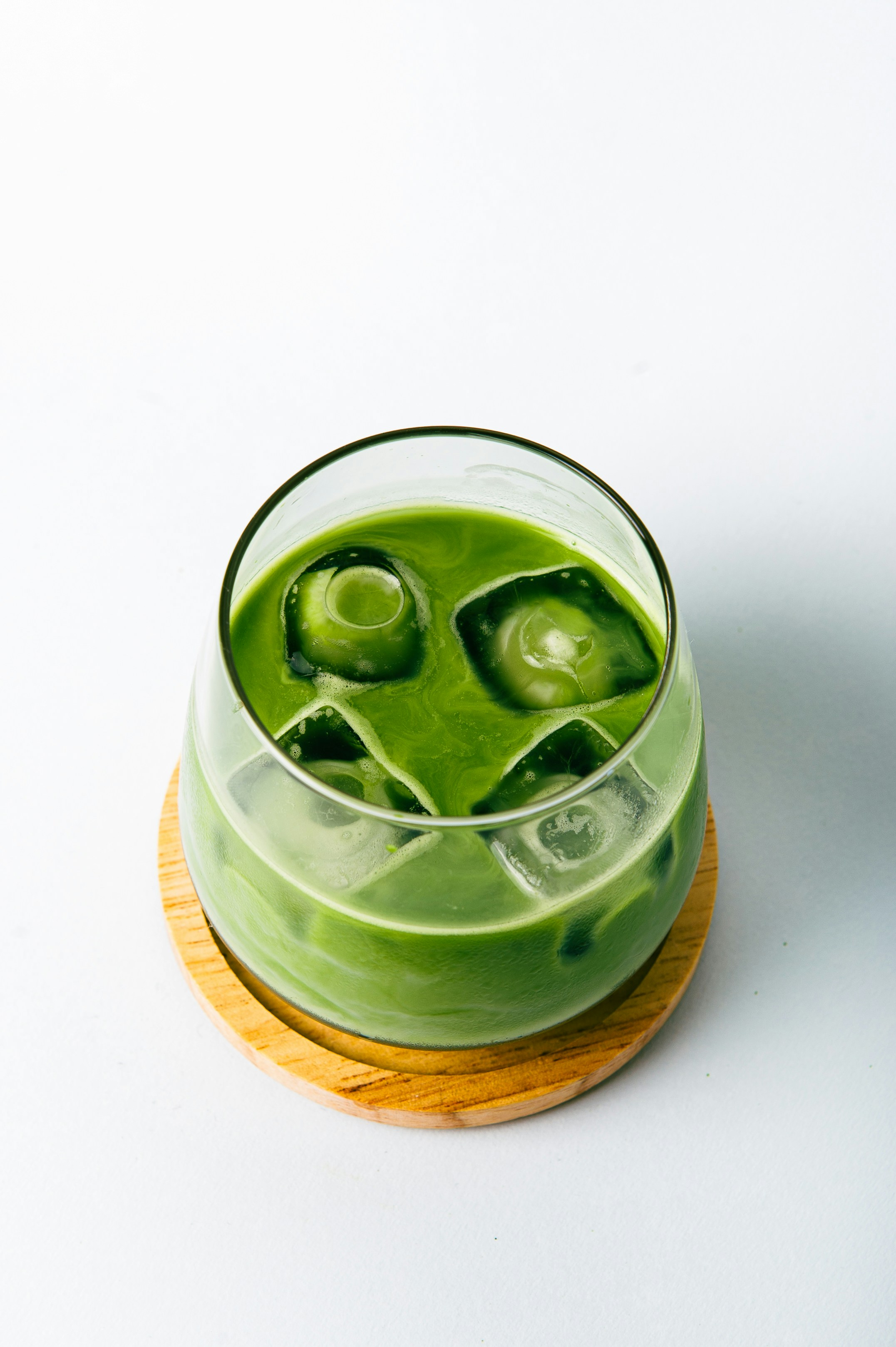 Iced matcha latte served over ice on a wooden coaster