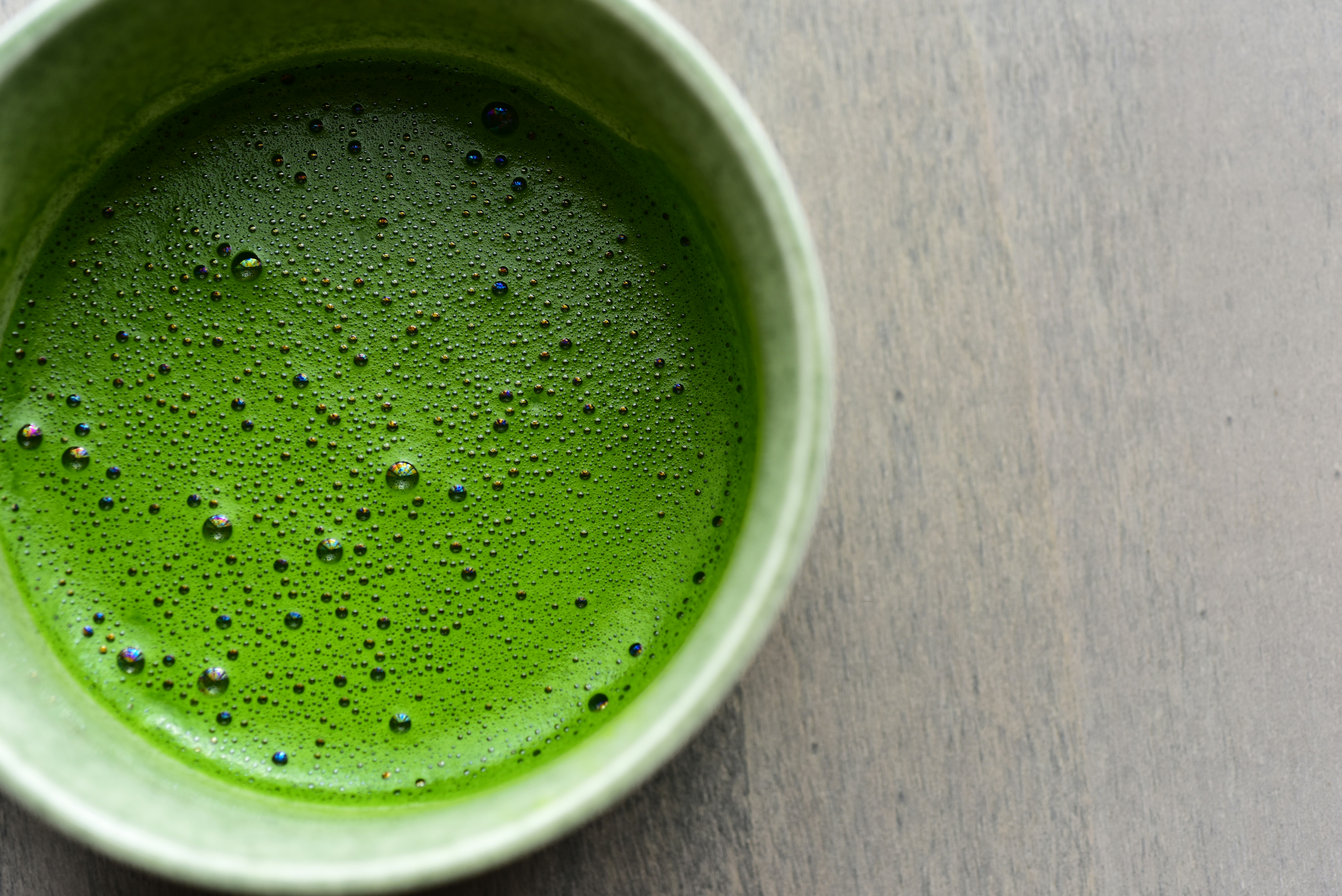 Close-up of fine matcha foam bubbles in a ceramic bowl
