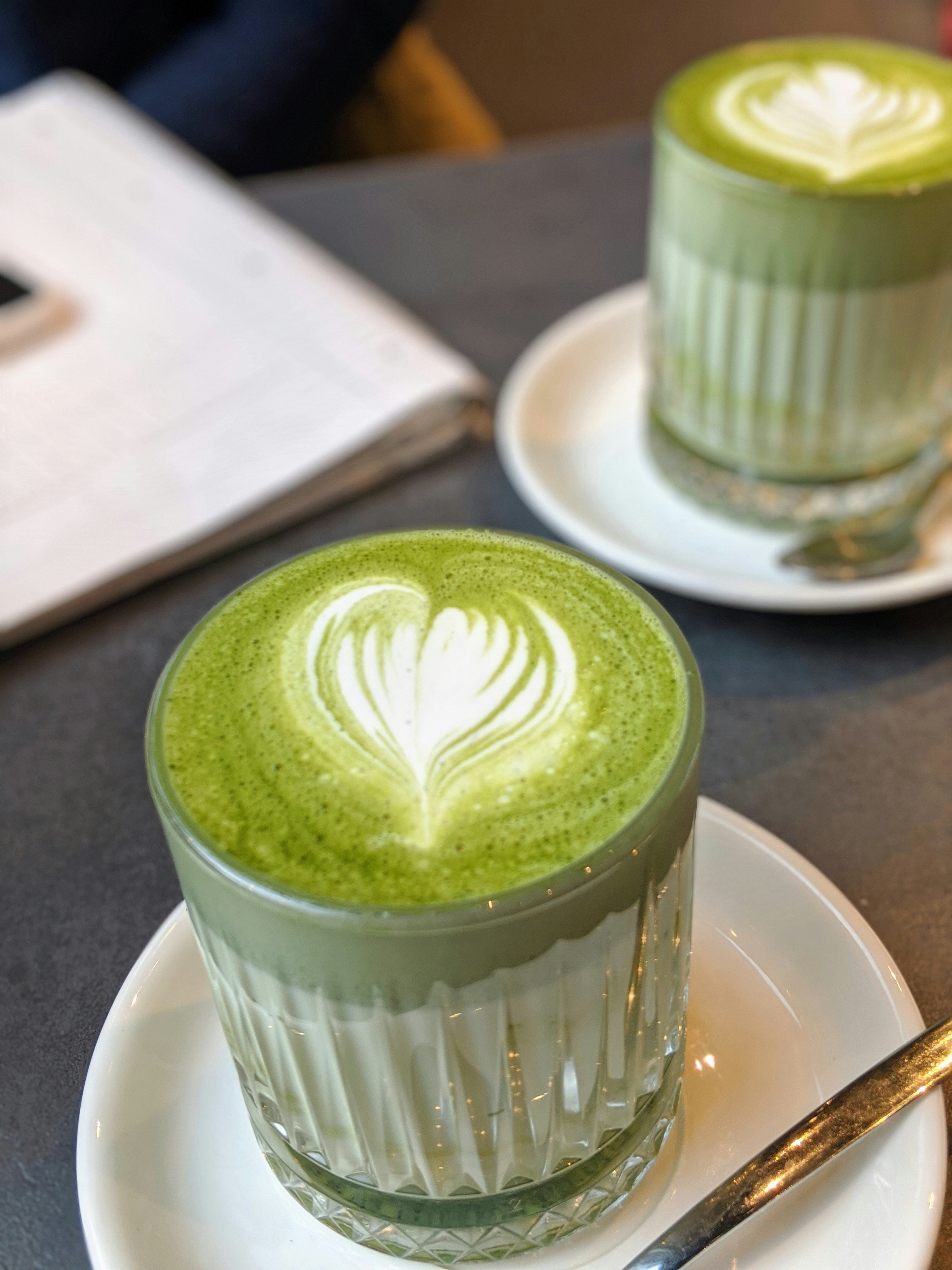 Matcha latte with heart-shaped latte art on a cafe counter