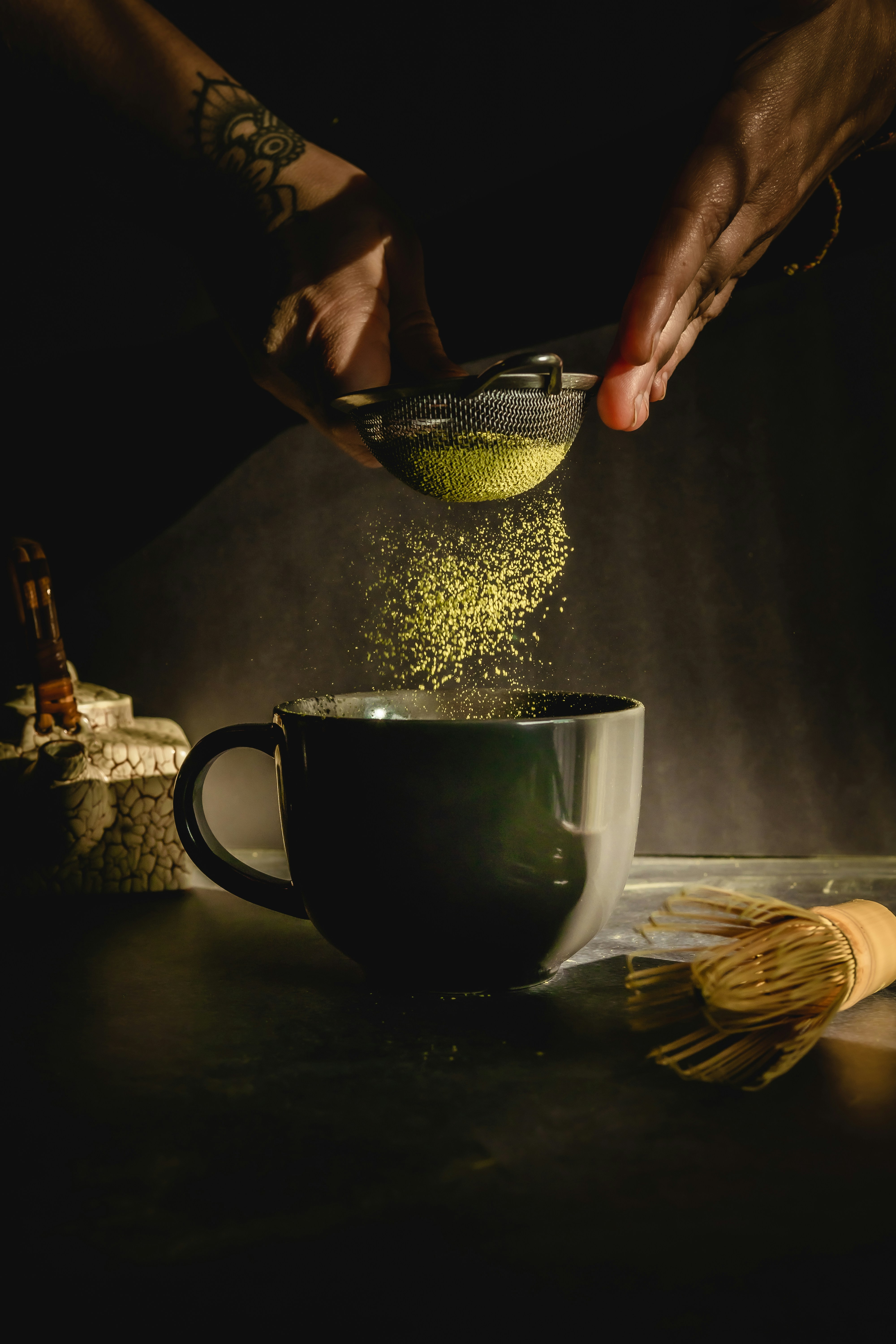 Fine matcha powder being sifted into a cup