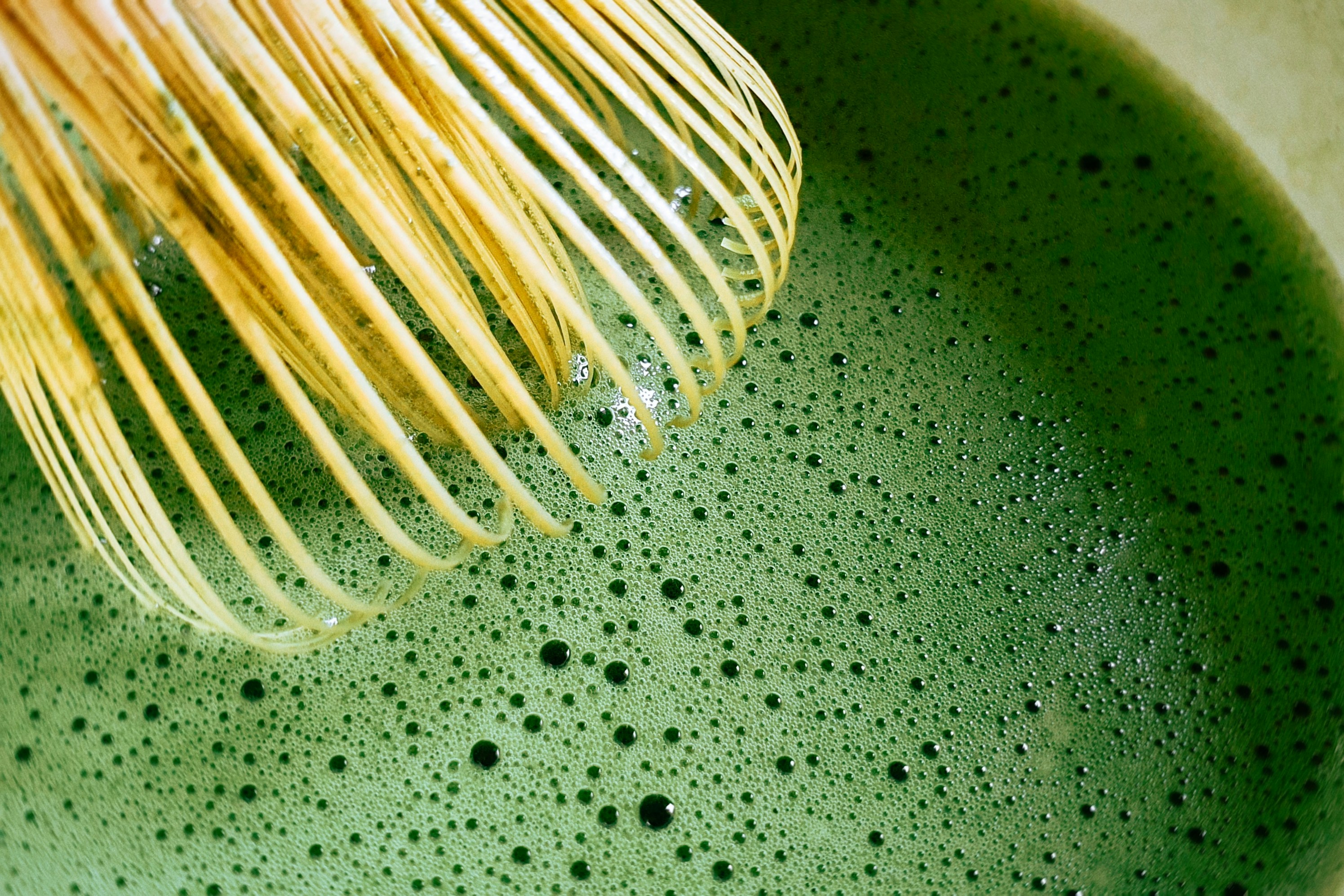 Macro close-up of fine matcha foam bubbles from a freshly whisked bowl